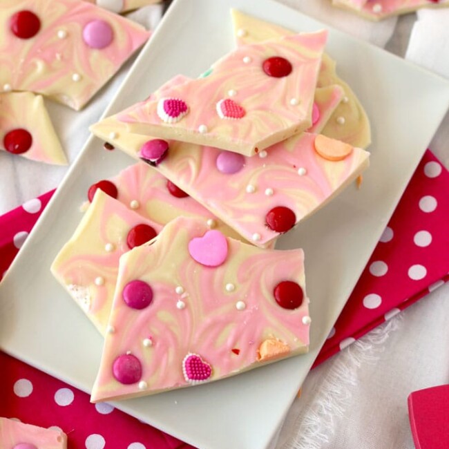 Pieces of white chocolate valentine's bark on a rectangular white plate.
