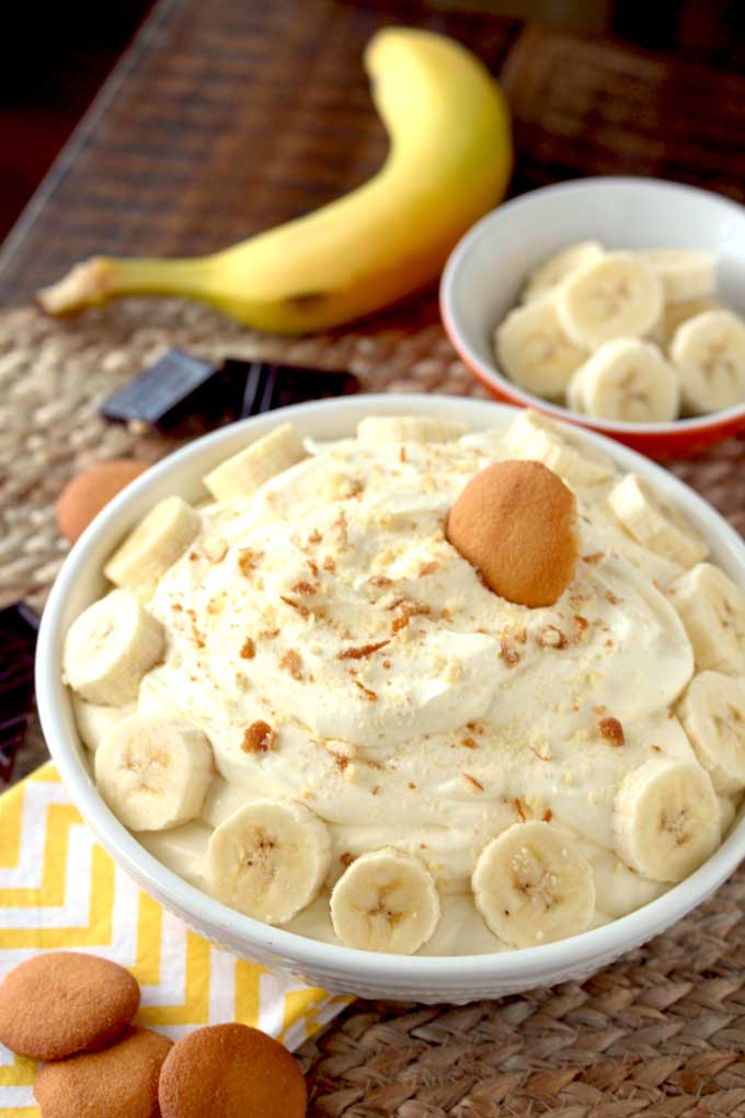 A bowl of fluffy and creamy banana cream pie dip garnished with sliced bananas and topped with nilla wafer crumbs