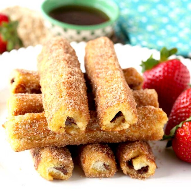 These Nutella French Toast Roll-Ups are a fun, finger-friendly treat for breakfast or brunch. These portable, and easy to make French Toast Roll Ups are filled with delicious Nutella, dunked into custard, sauteed until golden brown and then rolled in cinnamon sugar goodness!