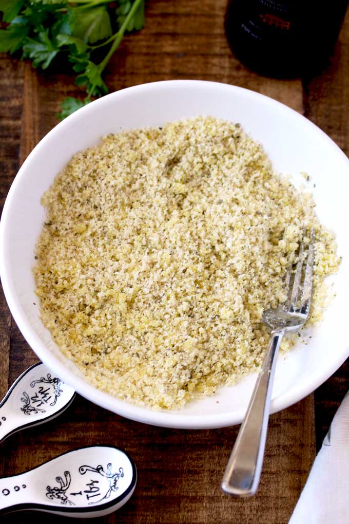 Parmesan Cheese, Panko bread crumbs and Italian seasoning mixed with olive oil in a white bowl.