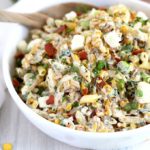 Mexican Street Corn Pasta Salad in a white bowl with a serving spoon.