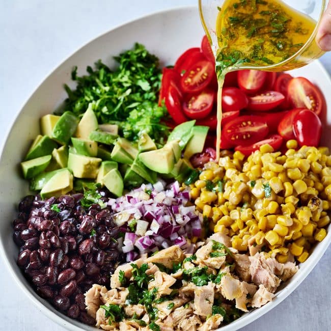 Pouring dressing over Mexican tuna salad in a bowl