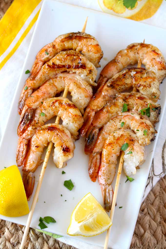 Two shrimp skewers on a white plate