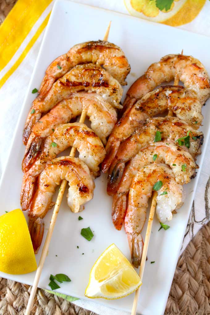 Two shrimp skewers on a white plate