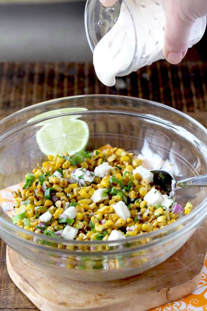 Creamy dressing pouring over corn salad
