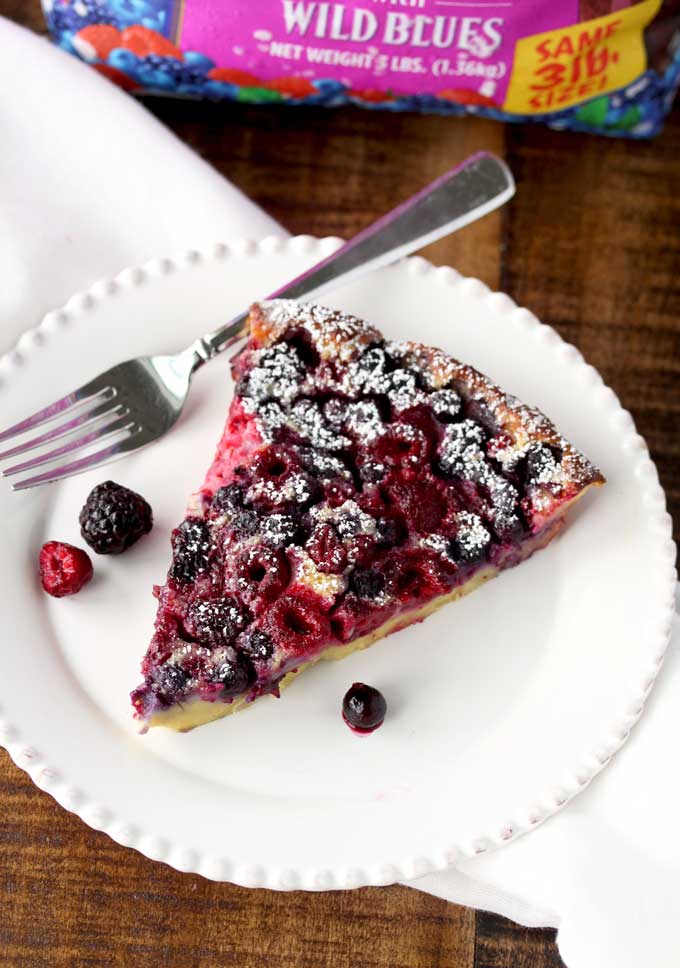 A big slice of mixed berry clafoutis on a white plate