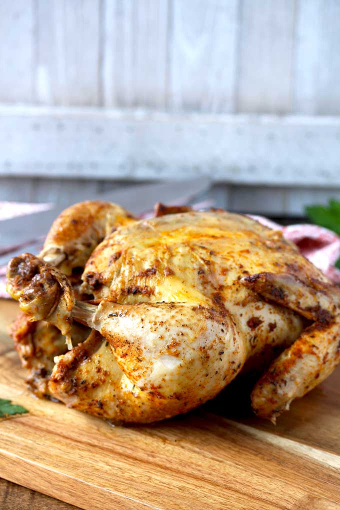 A whole chicken cooked in the instant pot on a wooden board