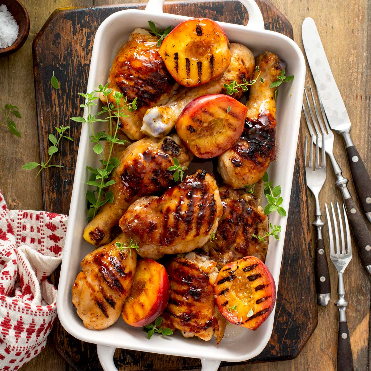 Ceramic white pan filled with peach glazed grilled bone-in chicken pieces.