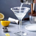 Cocktail shaker pouring a lemon drop cocktail in a martini glass