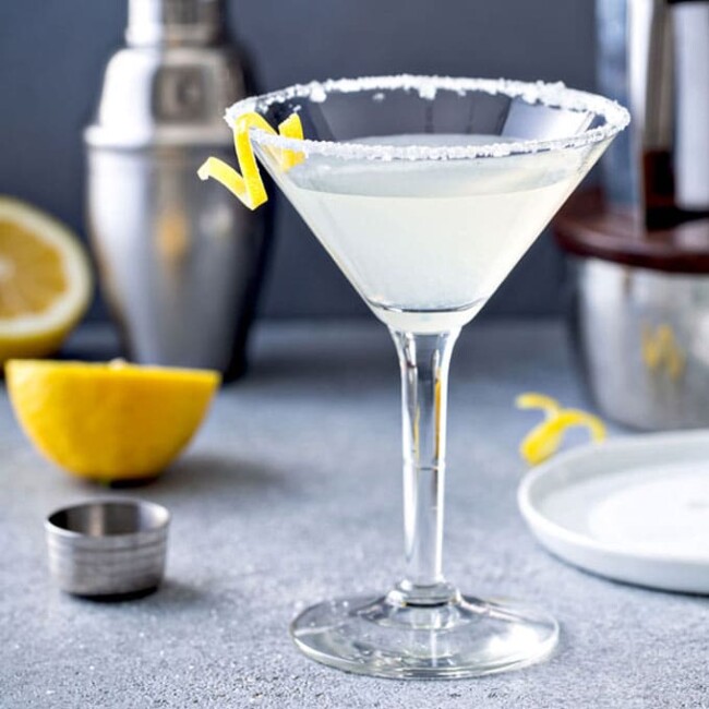 A glass of lemon drop martini cocktail with sugar on the martini glass and a lemon twist