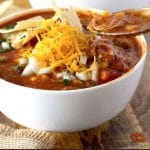 This Chicken Enchilada Soup is loaded with shredded chicken, black beans and corn and topped with your favorite fixings! This creamy, cheesy and hearty Enchilada Soup is made entirely in the slow cooker!