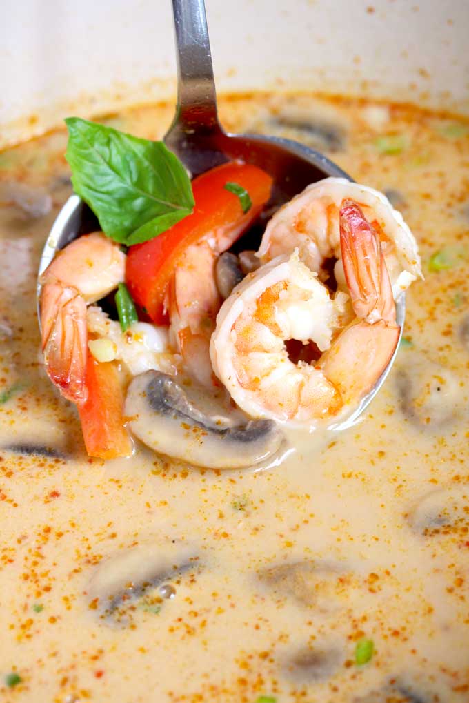 A laddle of coconut curry soup with shrimp.