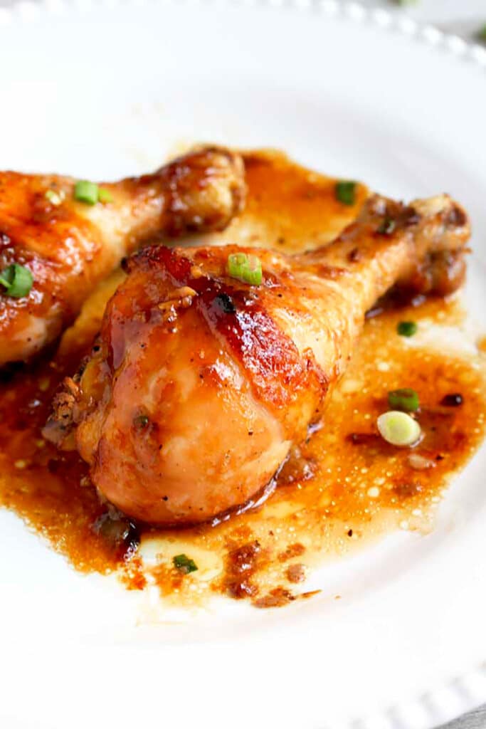 Golden brown baked chicken drumsticks with sweet and savory honey soy sauce on a white dinner plate