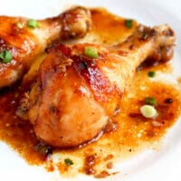 Golden brown baked chicken drumsticks with sweet and savory honey soy sauce on a white dinner plate