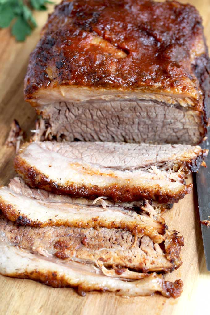 Slices of Instant Pot Brisket are been sliced on a cutting board.