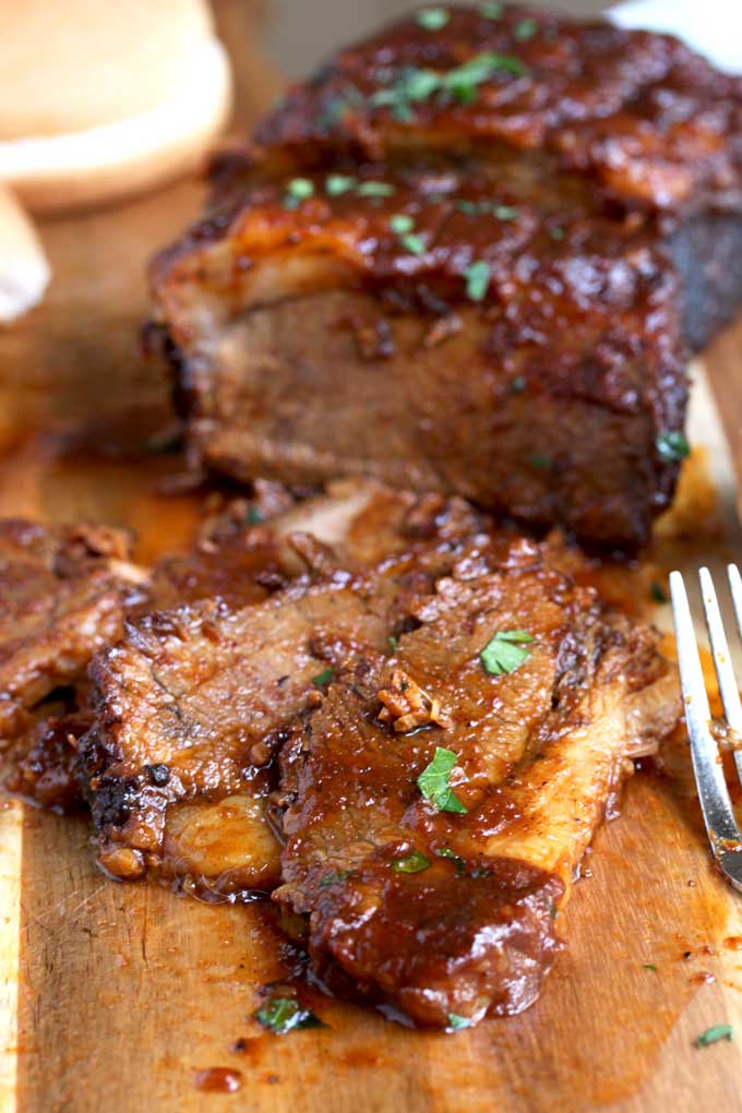 Instant Pot Brisket sliced thinly smothered in BBQ sauce on a cutting board