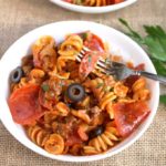 Pizza Pasta with pepperoni, sausage, olives and cheese in a white bowl.