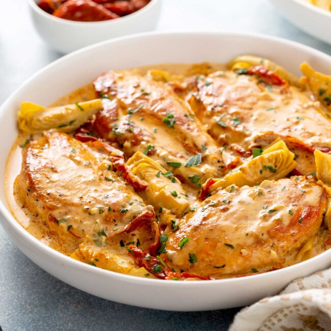 Chicken breast with sun dried tomatoes cream sauce in a white bowl