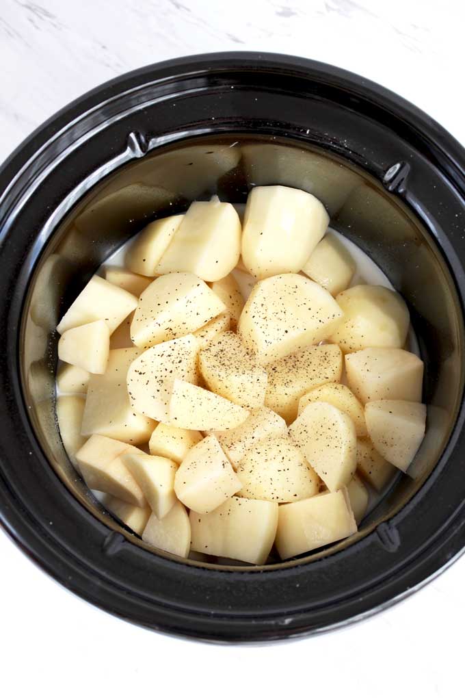 Chopped Potatoes with milk and broth in the crock pot.
