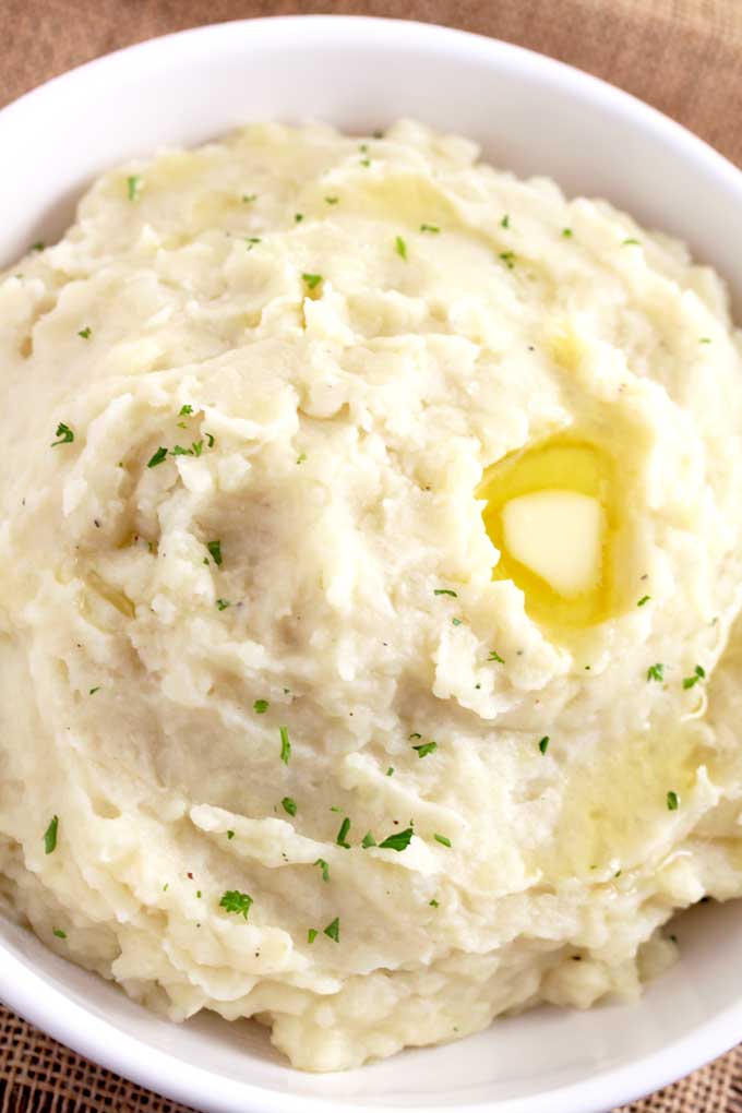 Top view of fluffy Slow Cooker Mashed Potatoes in a white bowl.