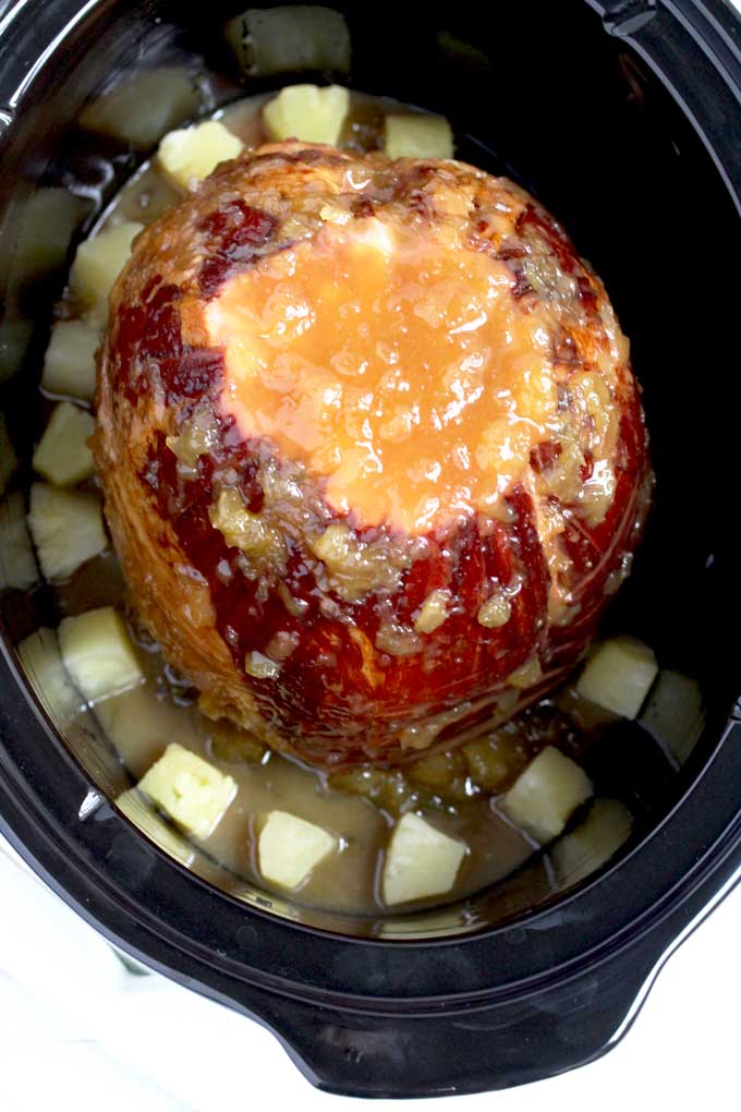 Ham inside a slow cooker and covered with glaze.