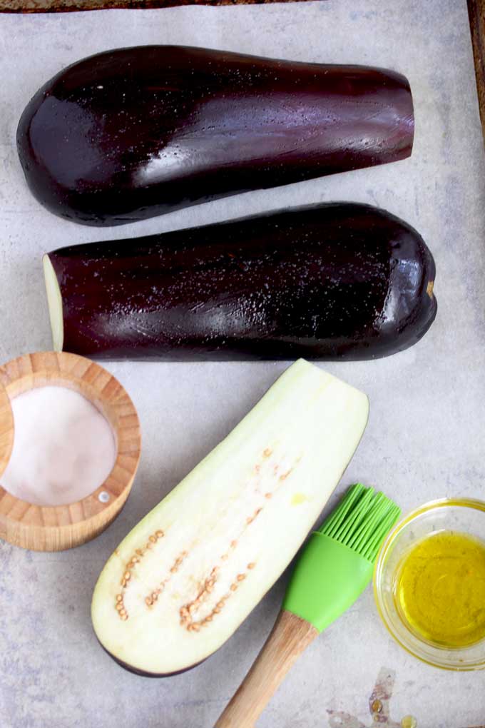 Eggplants, olive oil and salt on a baking sheet.