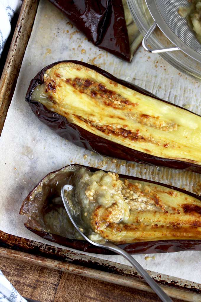 Removing the skin of a roasted eggplant.