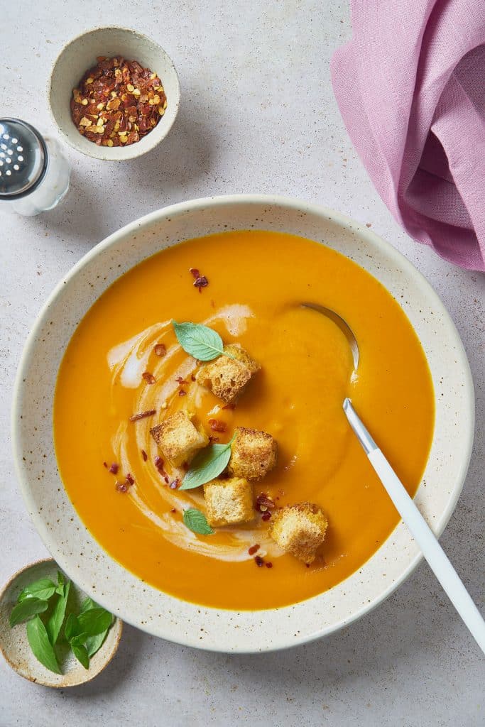Super creamy carrot soup topped with crispy croutons served in a soup bowl.