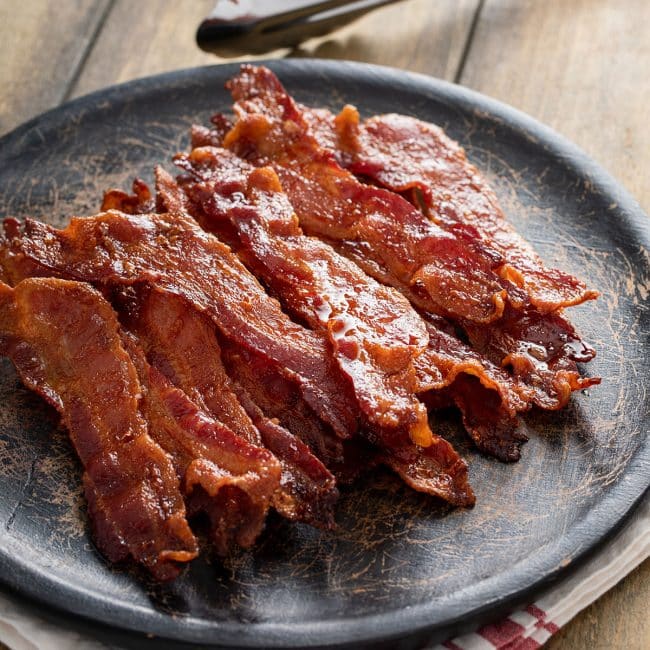 Crisp bacon slices on a black plate.