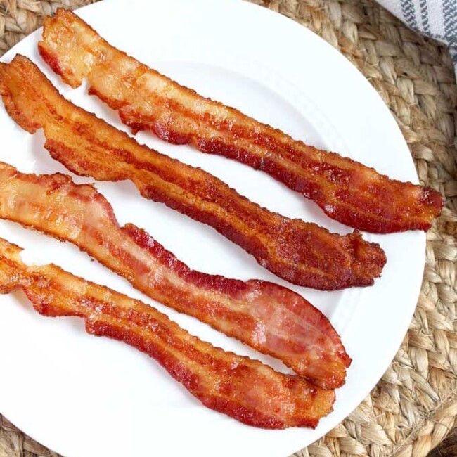 Crispy bacon slices on a white plate.