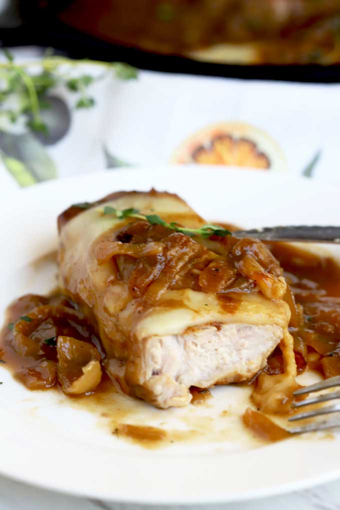 Pork Chop smothered in French onions with melted cheese cut up.
