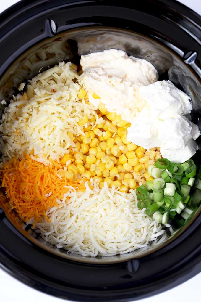 Ingredients to make corn dip inside a crock pot.