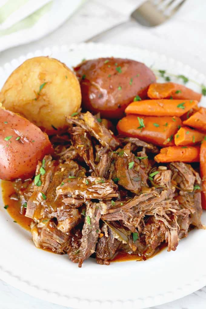 Instant Pot Pot Roast served with potatoes and carrots on a white plate.