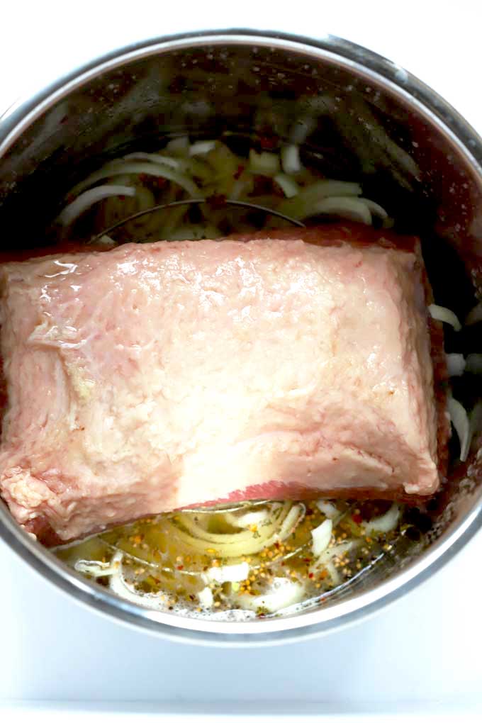 Corned beef brisket on a pressure cooker trivet with onions, garlic, pickling spices, beer and broth.