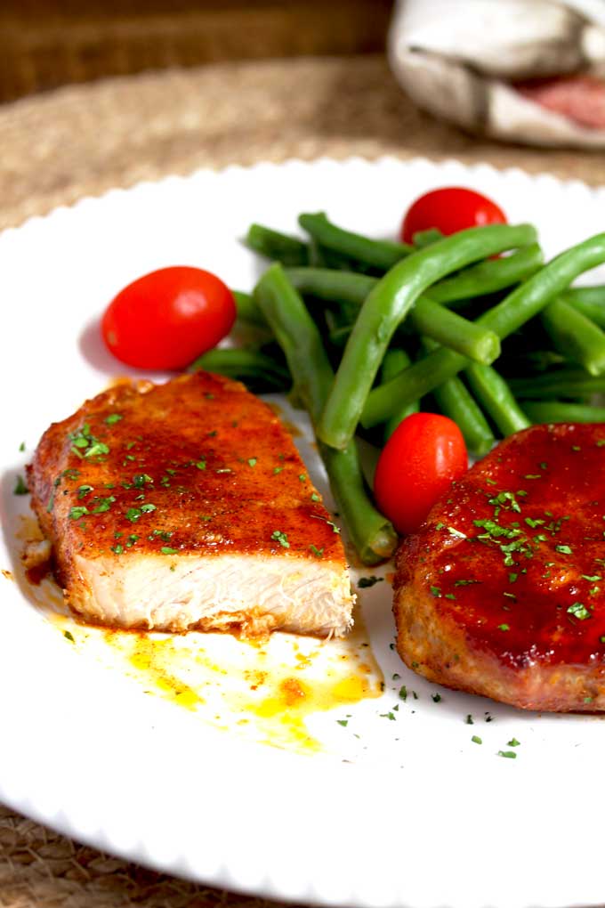 Baked Pork chop cut up served with green beans and tomatoes.