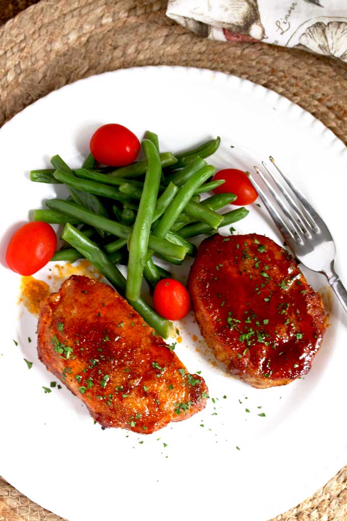 Baked pork chops served on a white plate.