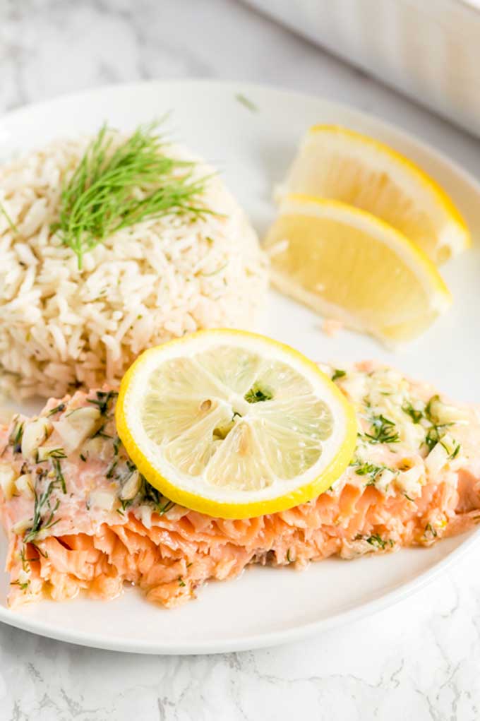 A piece of salmon served with rice and garnished with sliced lemons.