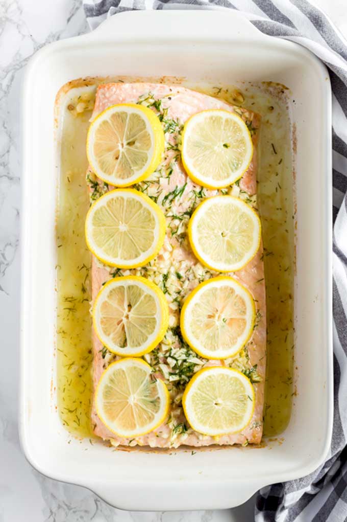 Top view of a baking dish with a filet of baked salmon.