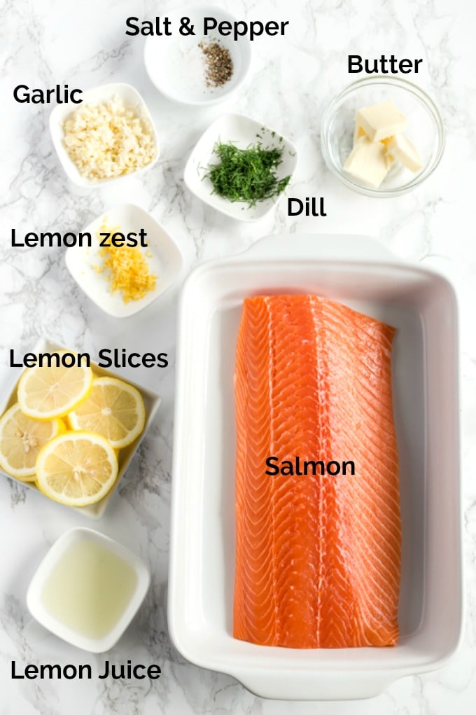 Ingredients to make baked salmon on a white surface.