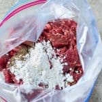 sliced steak in a plastics bag with cornstarch, black pepper and soy sauce.