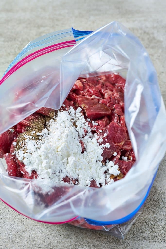 sliced steak in a plastics bag with cornstarch, black pepper and soy sauce.