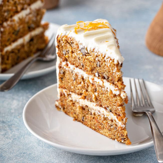 Slice of three layered carrot cake with cream cheese frosting