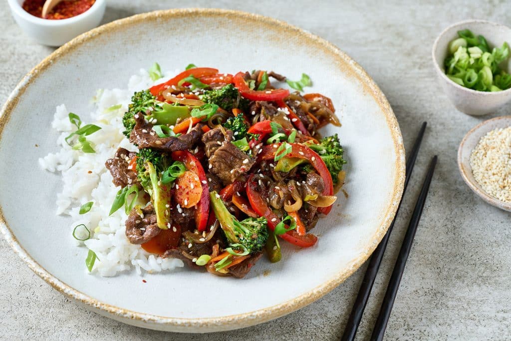 beef stir fry with white rice on a white plate