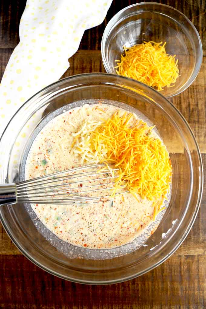 Quiche custard mixture and shredded cheese in a mixing bowl