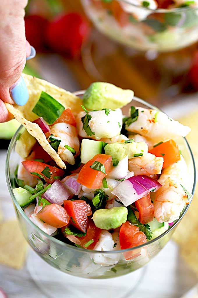 Scooping ceviche from a bowl with a tortilla chip