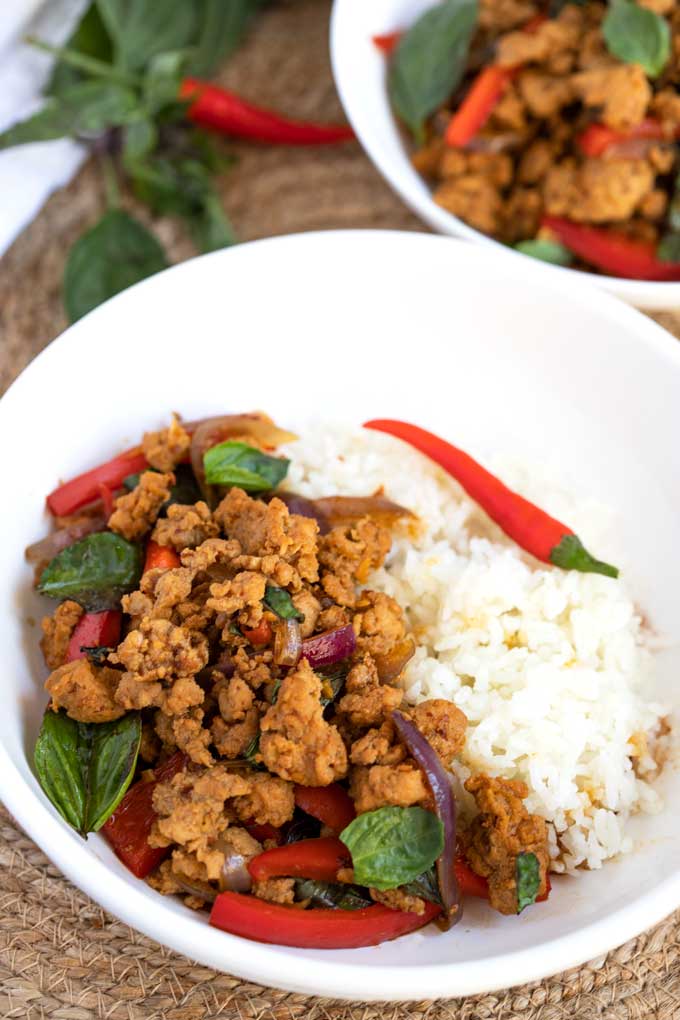 Mouthwatering Thai Basil Chicken served with rice in a white bowl.