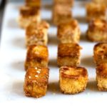Crispy golden brown tofu on a white serving board