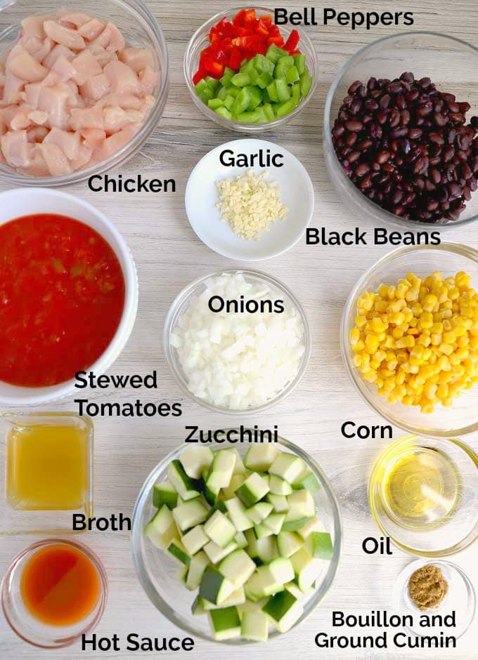 All the ingredients to make this tasty stew in small bowls on a white surface.