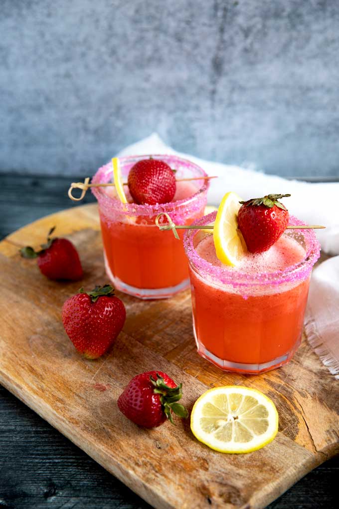 Strawberry Lemonade Vodka cocktail served in short glasses on top of a wooden board