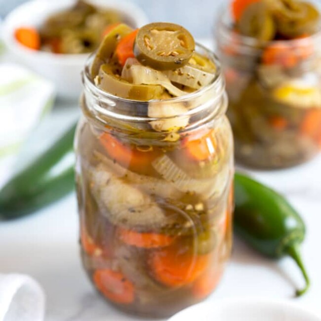 A jar of pickled jalapenos set among other jars.